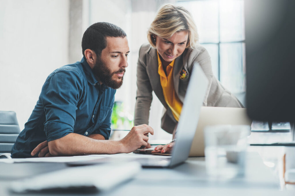 Two colleagues reviewing information together on a laptop