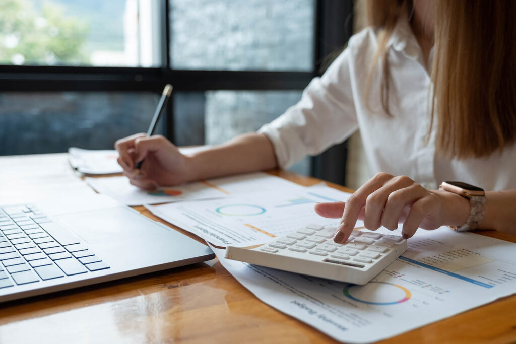 Person using calculator and reviewing charts at desk