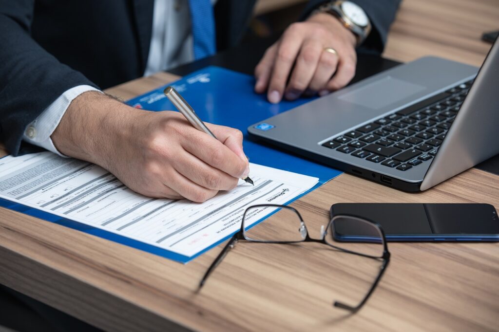Person signing financial document beside laptop illustrating inheritance tax planning