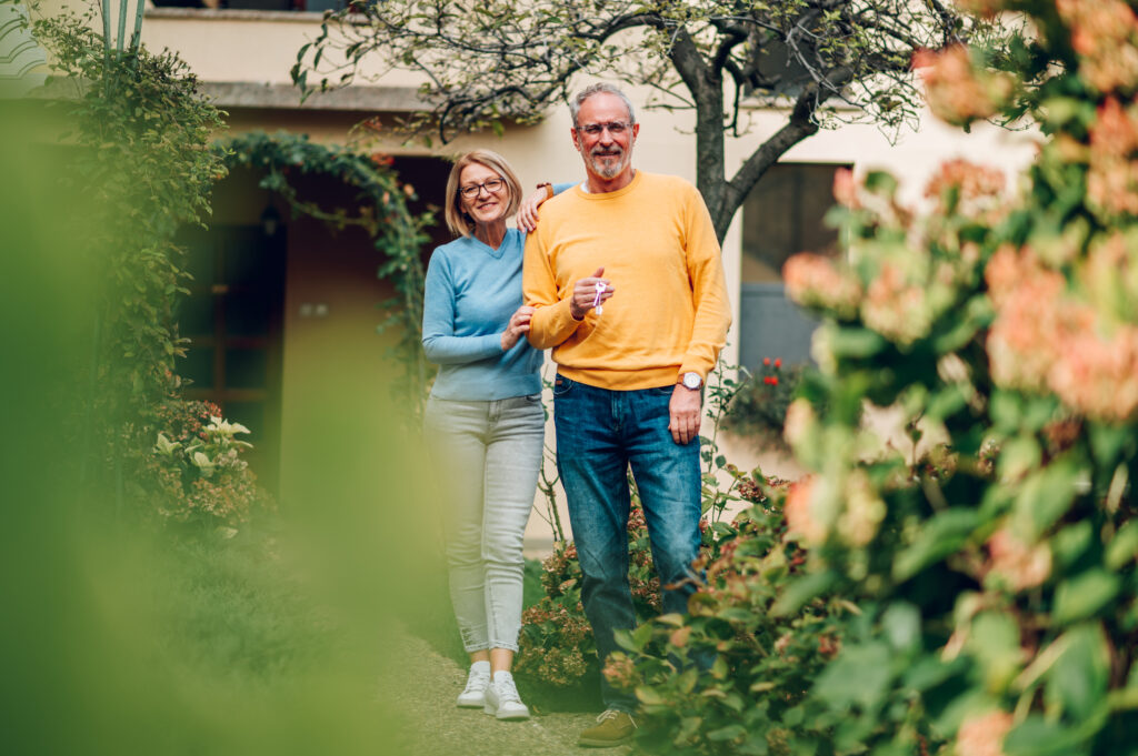 Senior couple standing outside a home and holding keys