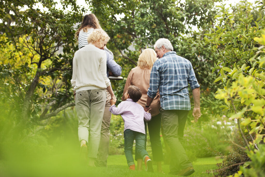 Multigenerational family walking together through a leafy garden