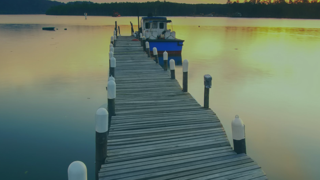 Calm lake scene with a wooden jetty and boat at sunset used as a YouTube thumbnail background